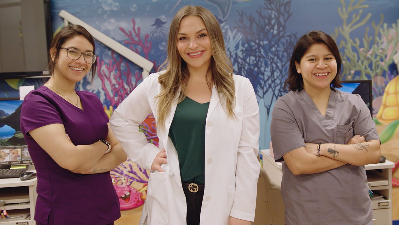 A dentist stands alongside her dental team in her practice.