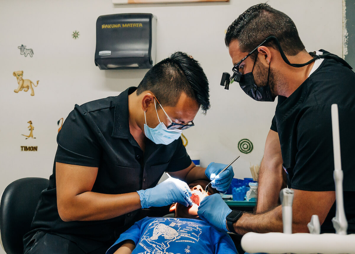 A dentist observes his mentor dentist as he checks a patient's teeth. Mentorship in dentistry is incredibly important to dentists that are just starting out!