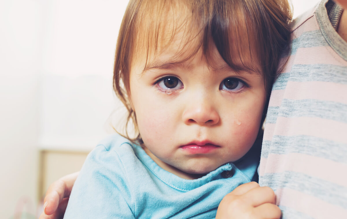 A toddler cries in her mother's arms at the dentist. Rural and underserved communities have more dental risk factors.