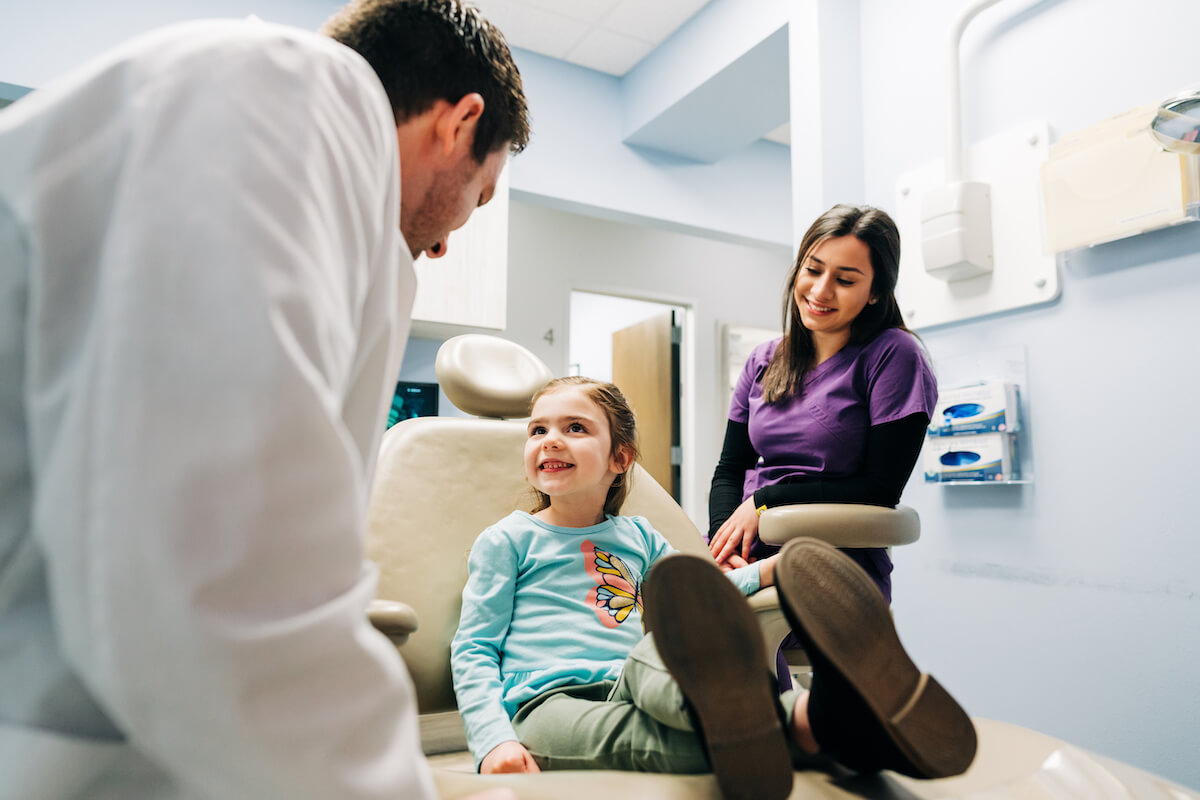 A dentist and dental hygienist work with a pediatric patient in their Texas dental practice.