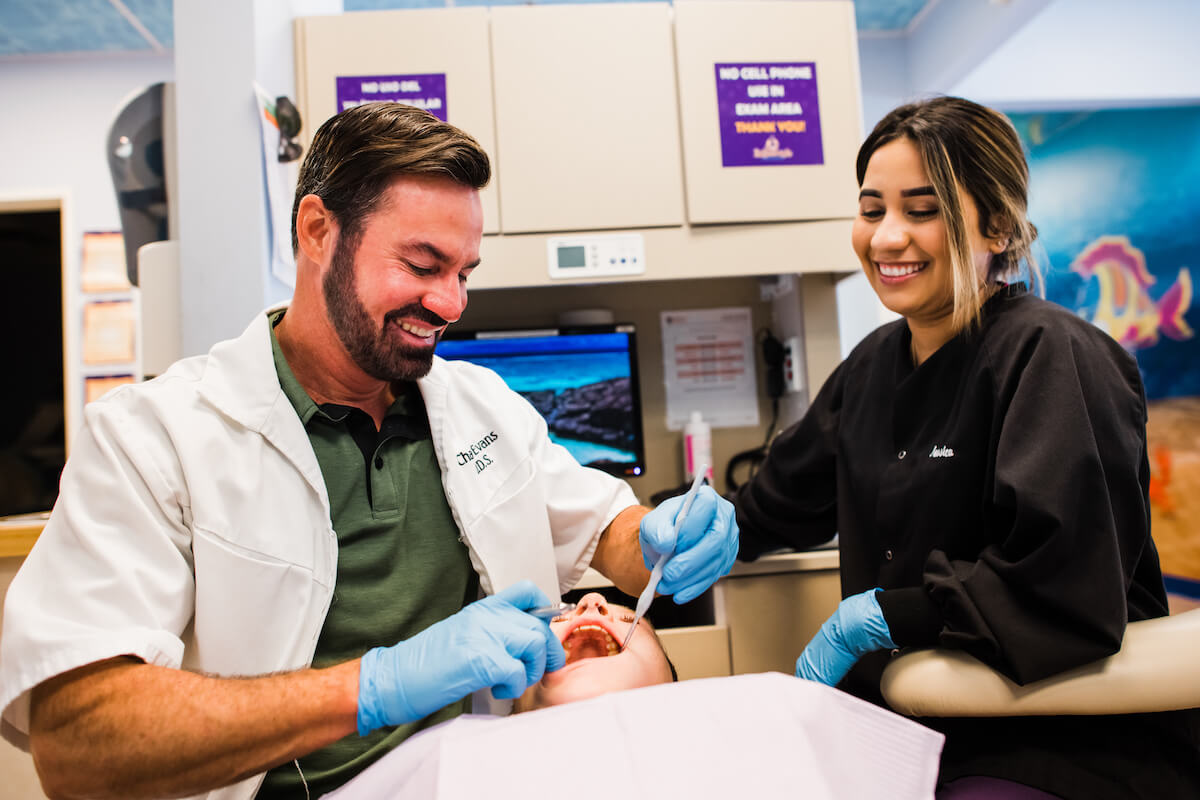 A dentist and hygienist perform a checkup on a pediatric patient in a practice managed by a dental DSO company.