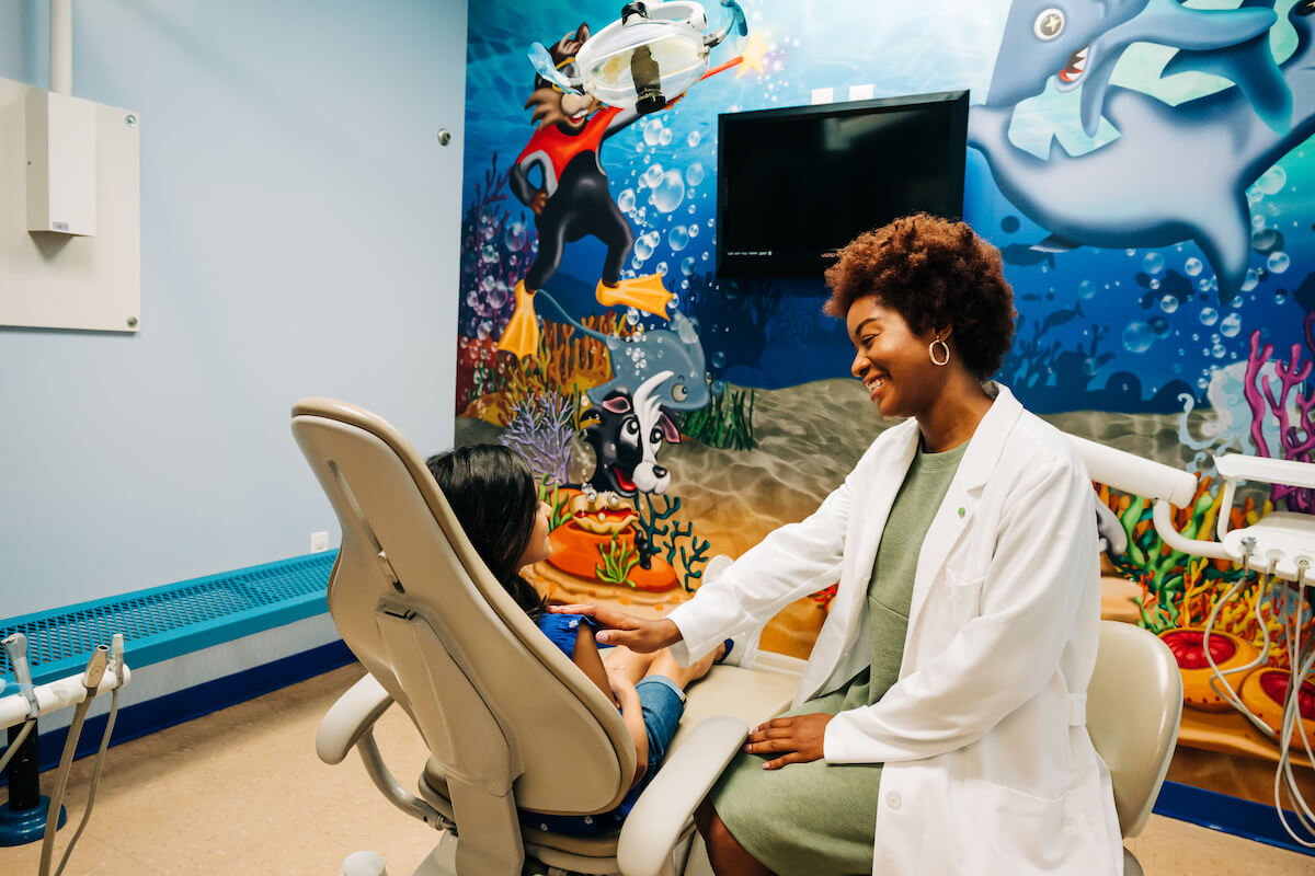 A dentist speaks with a pediatric patient at a practice managed by a dental DSO company.