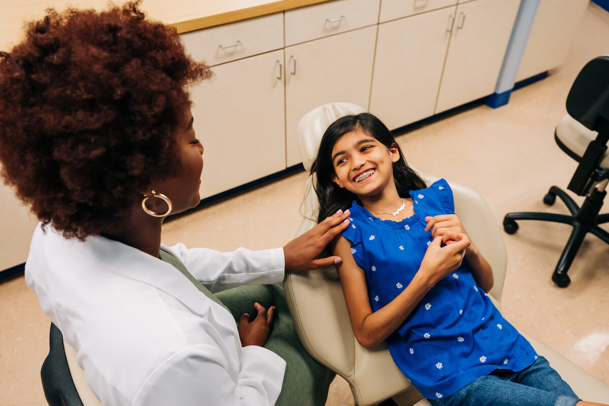 A dentist comforts a pediatric patient at her checkup. It's important to connect with patients and ease their worries, especially when they're young. Build a dental career you’ll love!