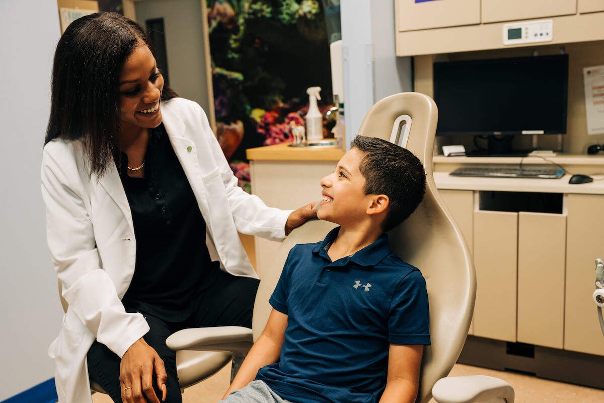 A new dentist sits with a pediatric patient, speaking with him and building their relationship.