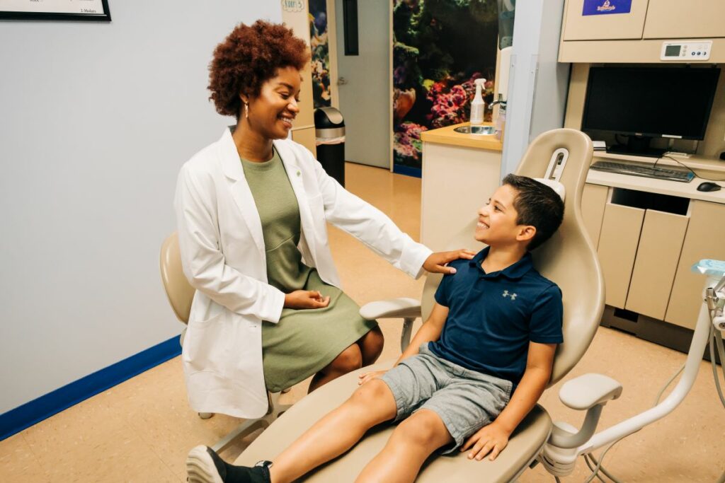 A female dentist comforting a young male as he sits in the dental chair.