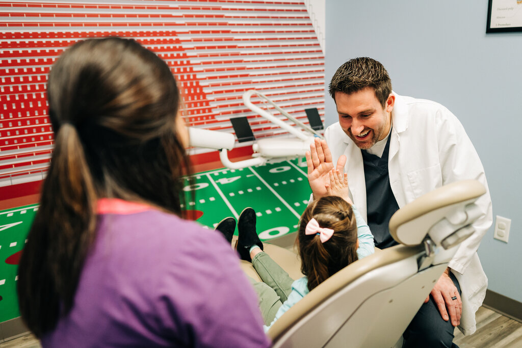 Pediatric dentist giving a young patient a high five.