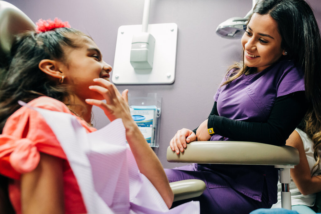 Hygienist sitting chairside with young female patient. 