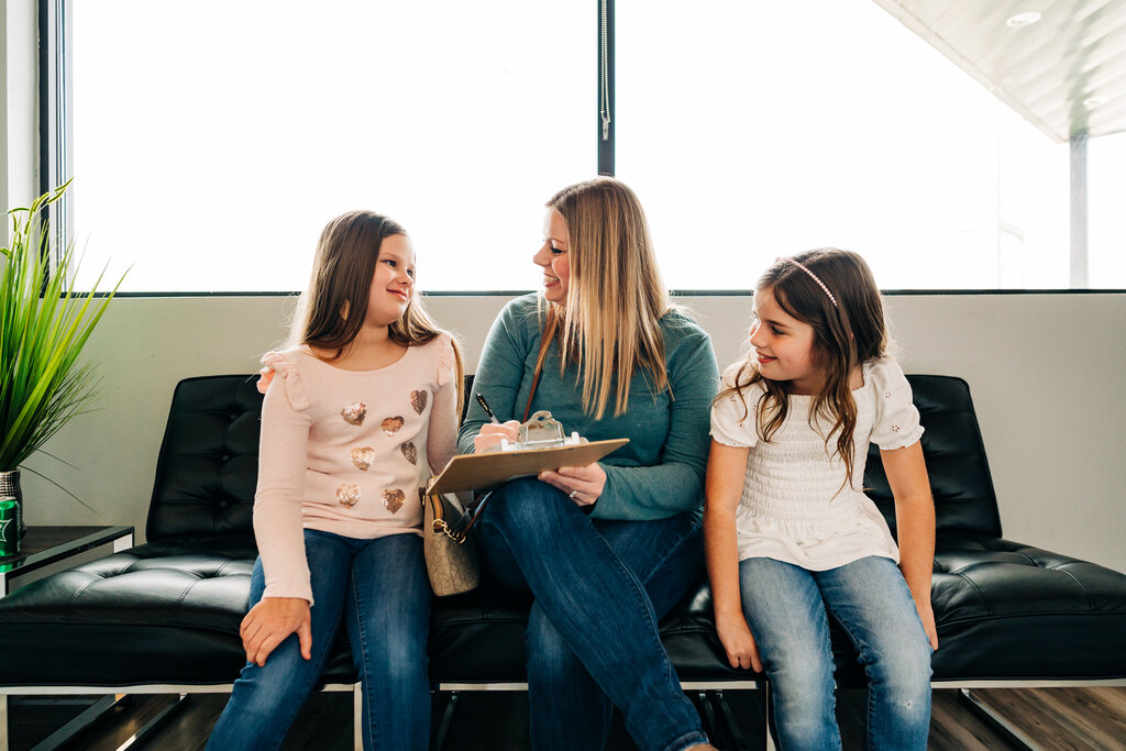 Mother and two daughters filling out paperwork in dental office. rthodontia is seen by many patients as a luxury or an extra treatment that is not necessary.